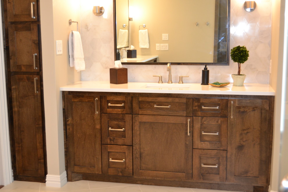 This is an example of a large transitional master bathroom in Dallas with shaker cabinets, medium wood cabinets, a freestanding tub, a corner shower, a two-piece toilet, white tile, marble, grey walls, porcelain floors, an undermount sink, quartzite benchtops, white floor and a hinged shower door.