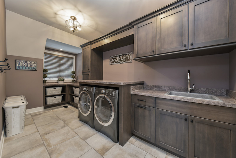 Large arts and crafts single-wall dedicated laundry room in Chicago with a drop-in sink, shaker cabinets, dark wood cabinets, laminate benchtops, purple walls, porcelain floors and a side-by-side washer and dryer.