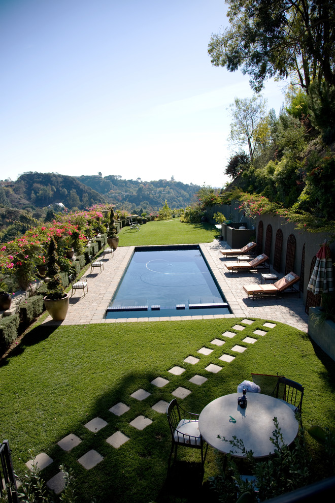 This is an example of a mediterranean backyard rectangular lap pool in Los Angeles with natural stone pavers.