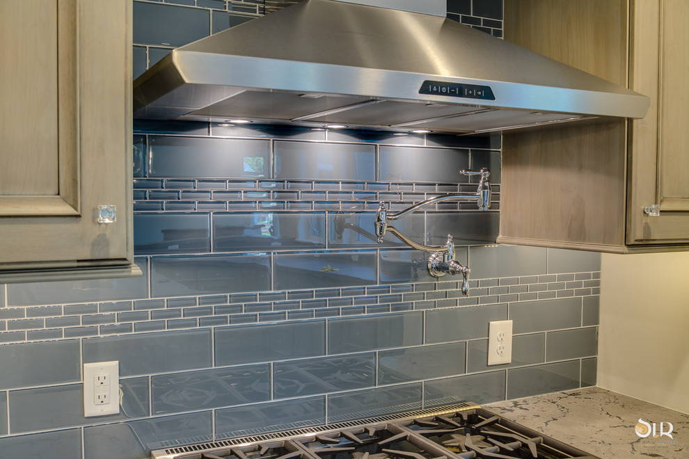Enclosed kitchen - transitional l-shaped medium tone wood floor and brown floor enclosed kitchen idea with an undermount sink, raised-panel cabinets, distressed cabinets, soapstone countertops, gray backsplash, subway tile backsplash, stainless steel appliances and an island