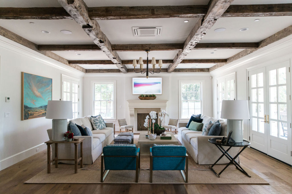 Photo of a traditional open concept family room in Other with white walls, medium hardwood floors, a standard fireplace, a wall-mounted tv, coffered and exposed beam.