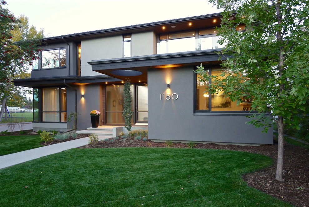 Photo of a large midcentury two-storey stucco brown exterior in Calgary with a hip roof.