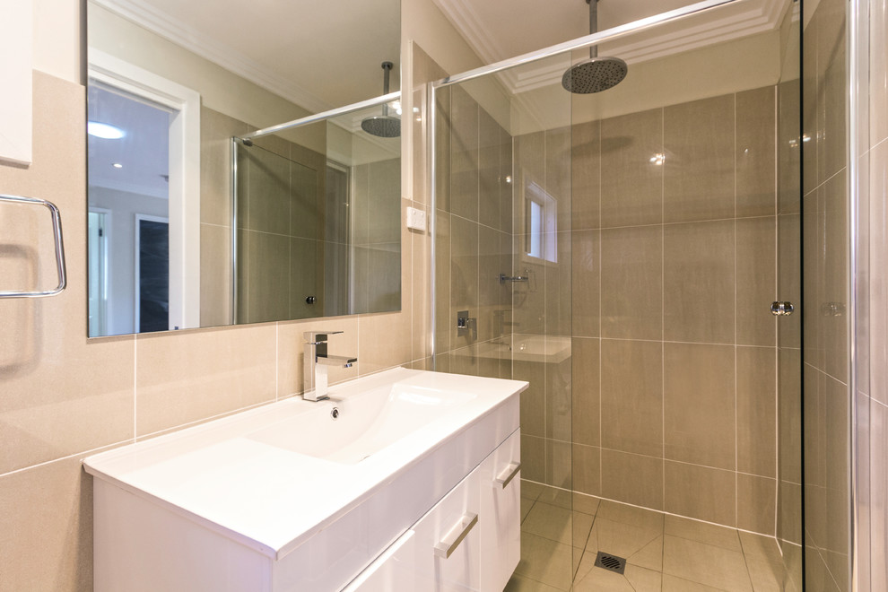 This is an example of a small contemporary 3/4 bathroom in Sydney with flat-panel cabinets, white cabinets, solid surface benchtops, an alcove shower, a one-piece toilet, brown tile, ceramic tile, white walls and ceramic floors.