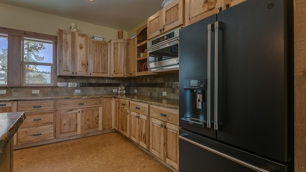 Example of a large mountain style u-shaped laminate floor and beige floor open concept kitchen design in Seattle with a farmhouse sink, raised-panel cabinets, light wood cabinets, granite countertops, multicolored backsplash, porcelain backsplash, black appliances, an island and multicolored countertops