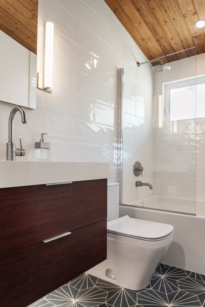 Design ideas for a small midcentury bathroom in Seattle with flat-panel cabinets, dark wood cabinets, a corner tub, a shower/bathtub combo, a one-piece toilet, white tile, ceramic tile, ceramic floors, engineered quartz benchtops, black floor, white benchtops, a single vanity, a floating vanity and wood.