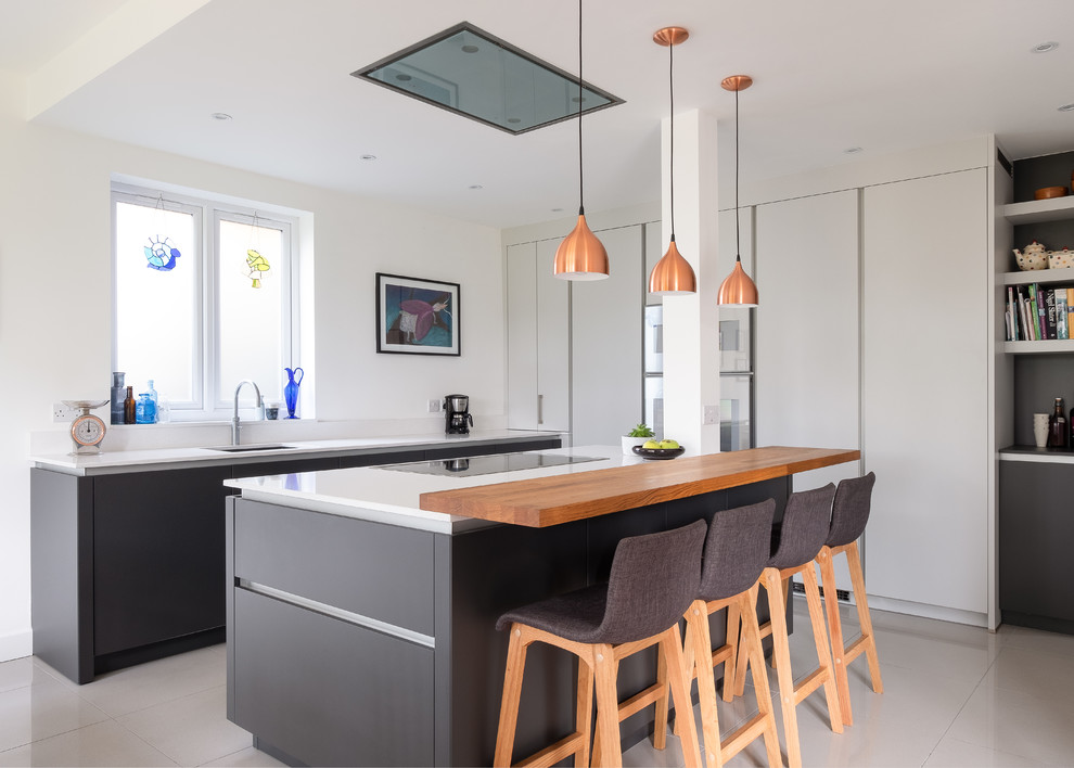 Design ideas for a large contemporary l-shaped eat-in kitchen in Gloucestershire with flat-panel cabinets, grey cabinets, quartzite benchtops, white splashback, porcelain floors, with island, white benchtop, an undermount sink and grey floor.