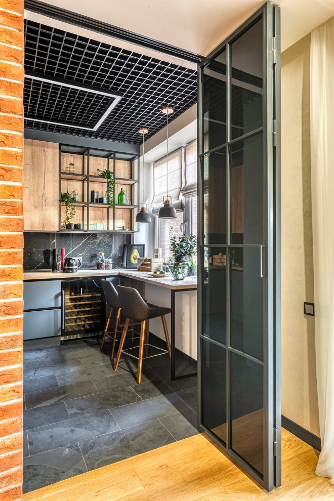 This is an example of a mid-sized contemporary galley separate kitchen in Moscow with an undermount sink, flat-panel cabinets, black cabinets, wood benchtops, black splashback, porcelain splashback, black appliances, marble floors, with island and brown benchtop.