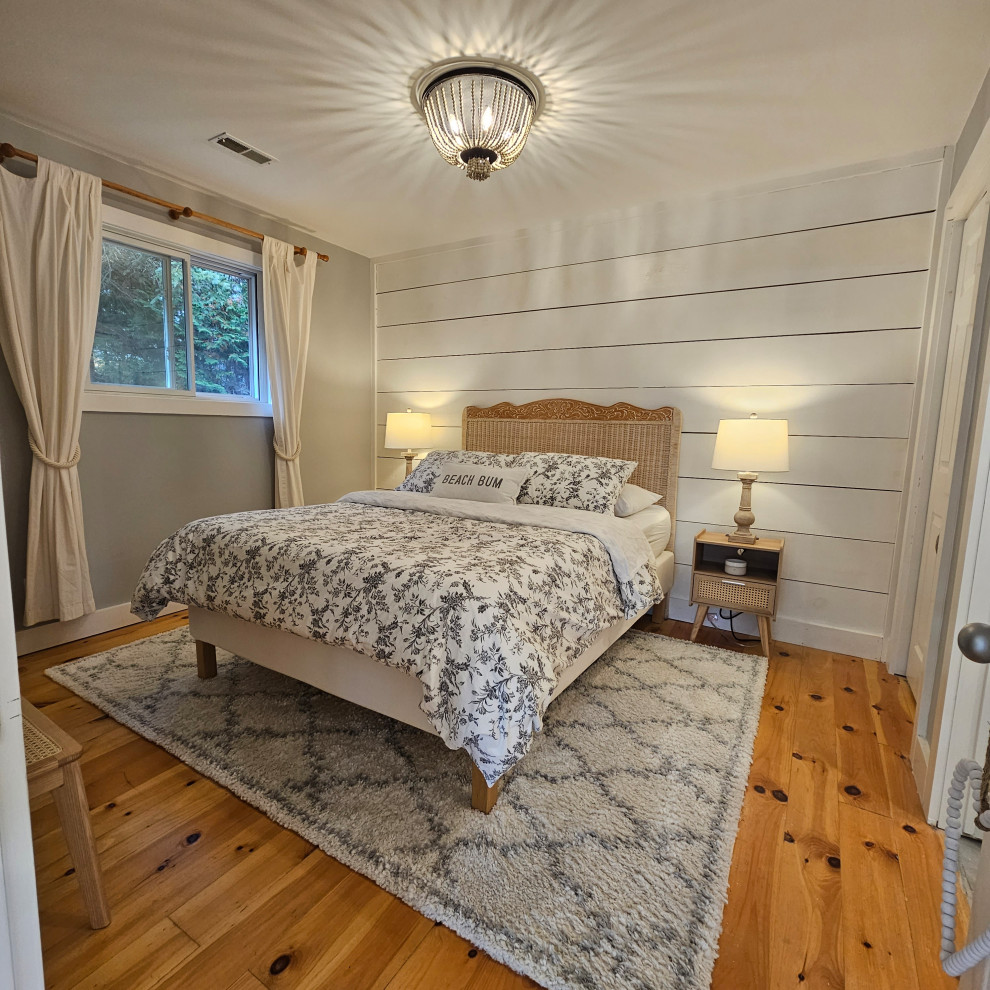 This is an example of a beach style master bedroom in Toronto with grey walls, medium hardwood flooring and tongue and groove walls.