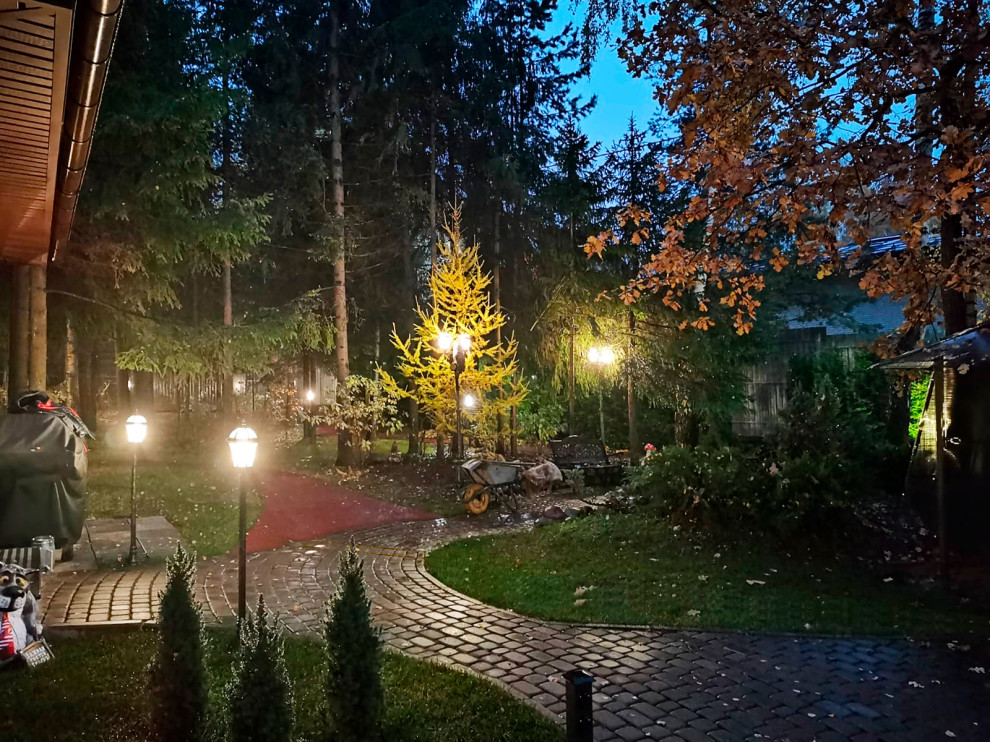 Photo of a mid-sized country courtyard partial sun driveway for fall in Moscow with with path, concrete pavers and a metal fence.
