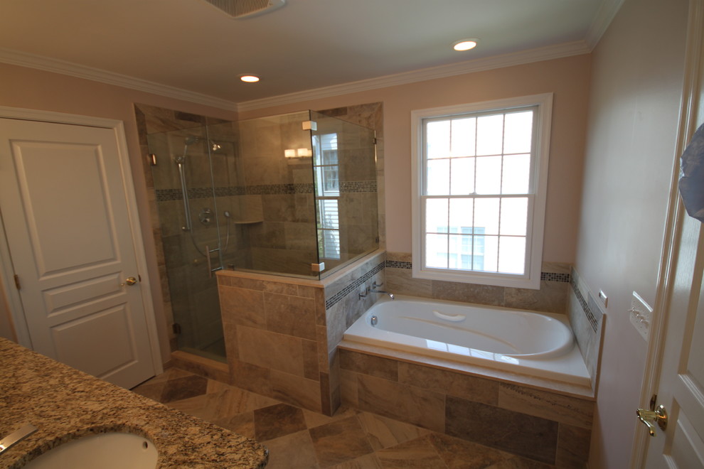 This is an example of a traditional bathroom in New York with an undermount sink, shaker cabinets, dark wood cabinets, granite benchtops, a drop-in tub, a corner shower, a two-piece toilet and beige tile.