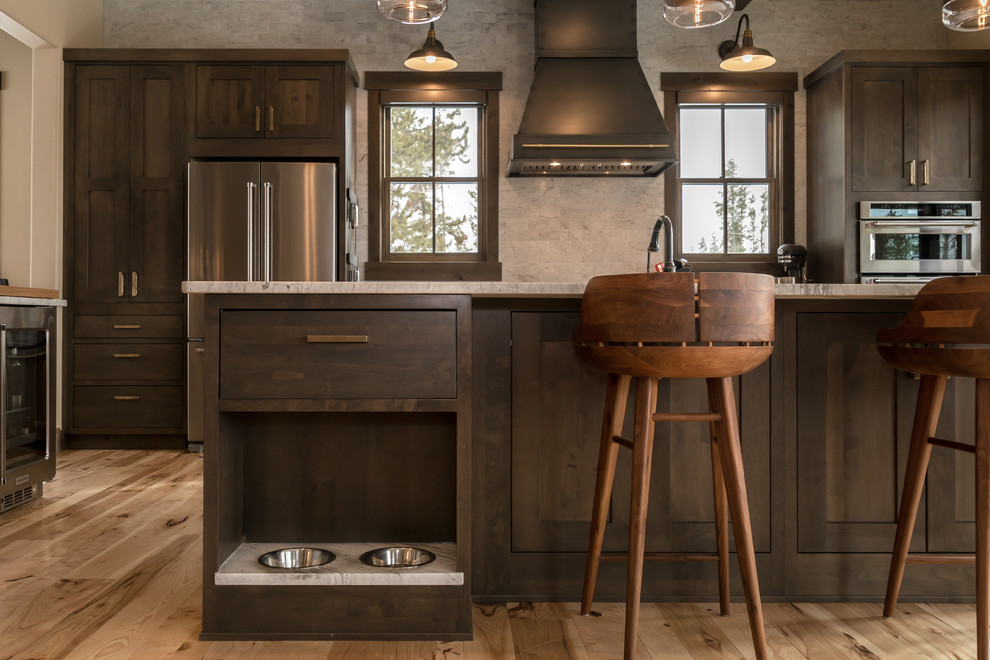 Inspiration for a large rustic l-shaped light wood floor and beige floor open concept kitchen remodel in Denver with an undermount sink, shaker cabinets, dark wood cabinets, quartz countertops, beige backsplash, subway tile backsplash, stainless steel appliances, an island and white countertops