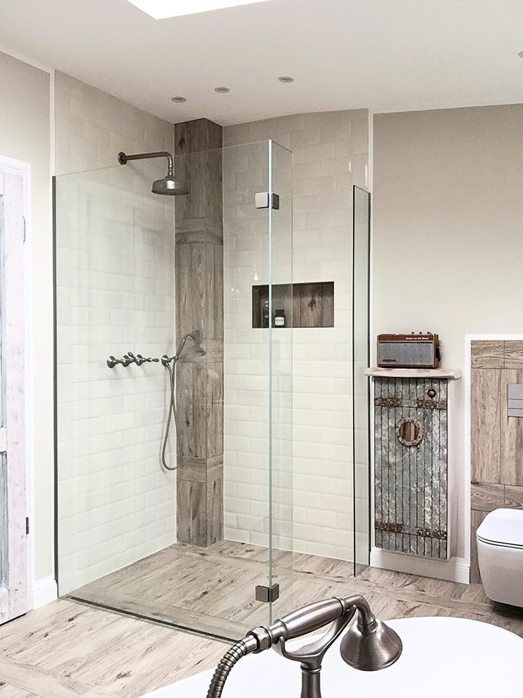Photo of a mid-sized industrial master bathroom in Berlin with recessed-panel cabinets, distressed cabinets, a freestanding tub, a curbless shower, a wall-mount toilet, beige tile, subway tile, beige walls, ceramic floors and a vessel sink.