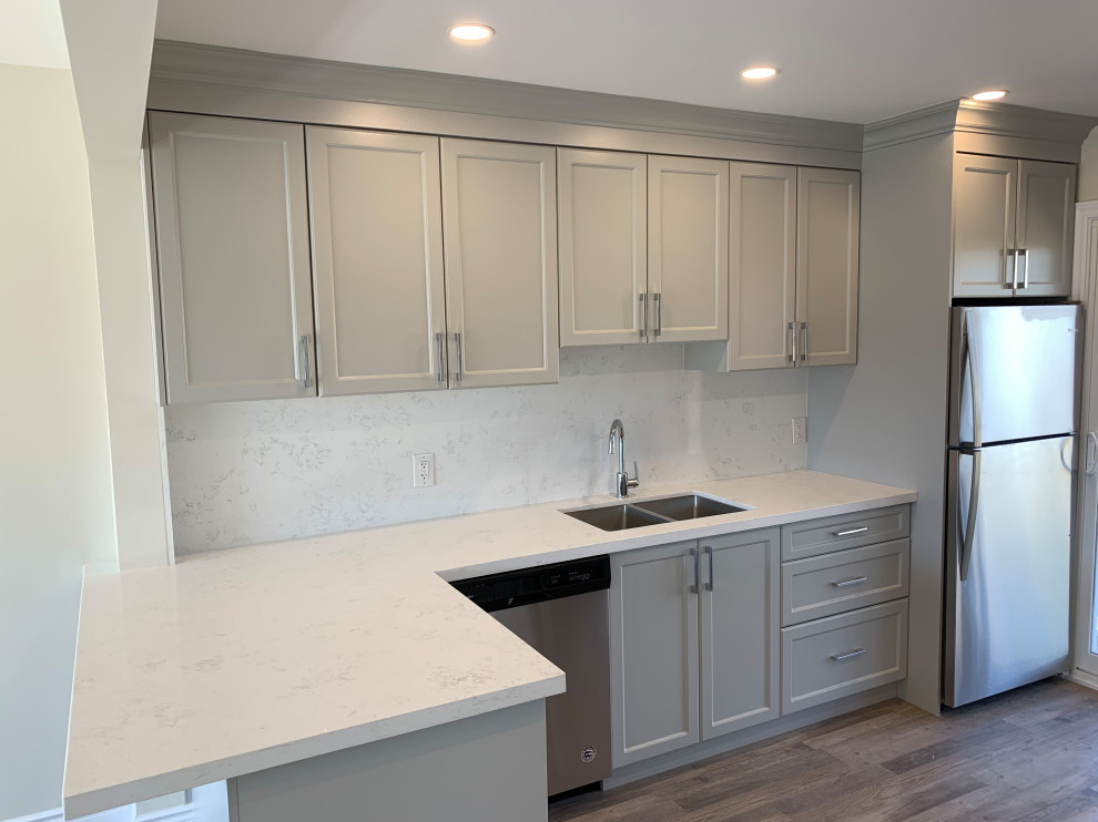 Mid-sized transitional galley medium tone wood floor eat-in kitchen photo with an undermount sink, shaker cabinets, gray cabinets, quartz countertops, white backsplash, quartz backsplash, stainless steel appliances, a peninsula and white countertops