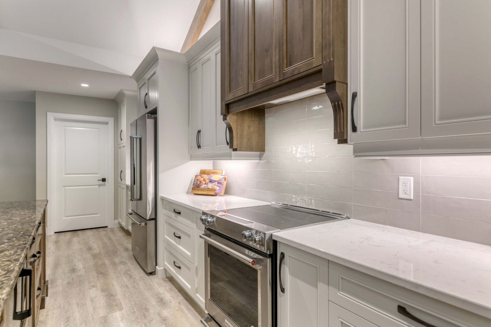 Example of a large transitional eat-in kitchen design with an undermount sink, shaker cabinets, quartz countertops, porcelain backsplash, stainless steel appliances and an island
