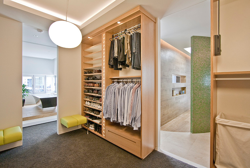 Photo of a contemporary men's dressing room in Los Angeles with open cabinets, light wood cabinets and carpet.