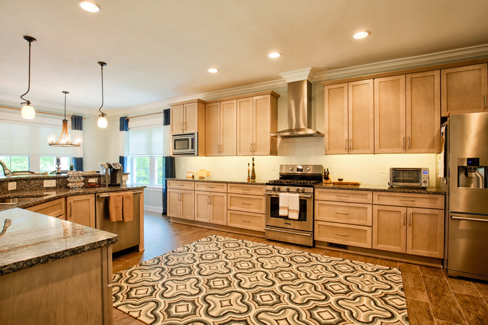 Large transitional single-wall porcelain tile and brown floor open concept kitchen photo with an undermount sink, recessed-panel cabinets, light wood cabinets, granite countertops, white backsplash, subway tile backsplash, stainless steel appliances, an island and gray countertops