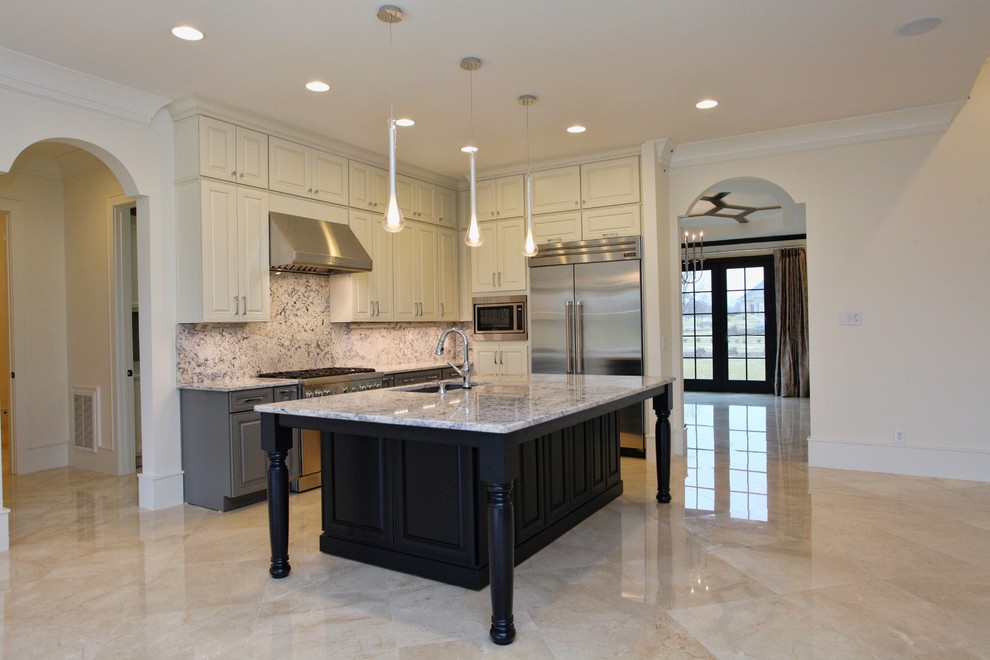 This is an example of an expansive transitional l-shaped open plan kitchen in Raleigh with a single-bowl sink, recessed-panel cabinets, granite benchtops, stainless steel appliances, marble floors, with island, stone tile splashback, white cabinets and multi-coloured splashback.