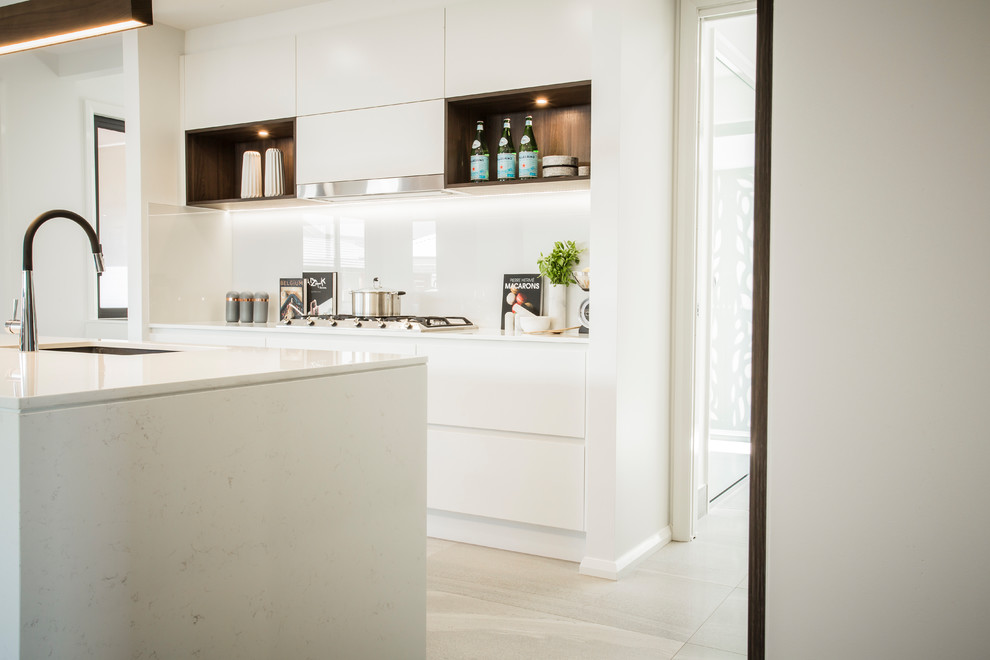 Large contemporary galley open plan kitchen in Sydney with a drop-in sink, louvered cabinets, dark wood cabinets, quartz benchtops, white splashback, glass sheet splashback, stainless steel appliances, bamboo floors and with island.