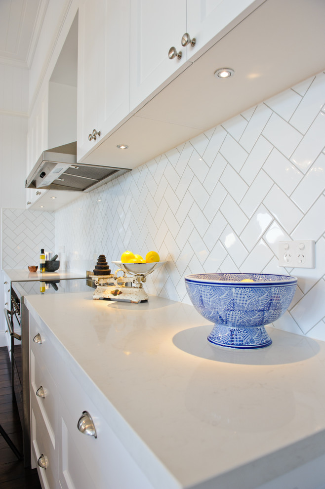 Mid-sized country single-wall open plan kitchen in Brisbane with a farmhouse sink, shaker cabinets, white cabinets, granite benchtops, white splashback, subway tile splashback, stainless steel appliances, dark hardwood floors and with island.