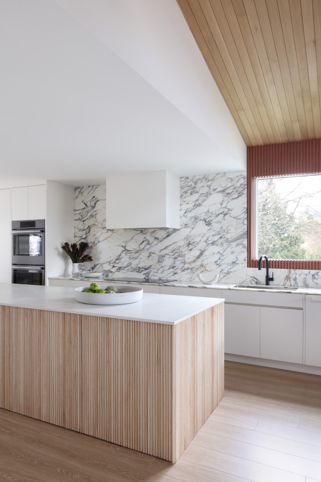 Inspiration for a midcentury eat-in kitchen in Vancouver with flat-panel cabinets, white cabinets, quartz benchtops, white splashback, marble splashback, black appliances, laminate floors, with island, white benchtop and wood.