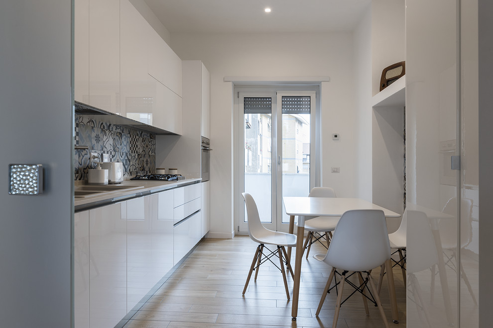 Inspiration for a contemporary single-wall separate kitchen in Rome with a double-bowl sink, flat-panel cabinets, white cabinets, multi-coloured splashback, stainless steel appliances, light hardwood floors, no island, beige floor and white benchtop.