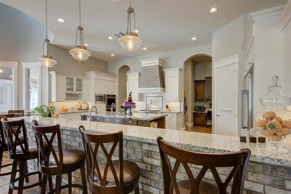 Large transitional u-shaped enclosed kitchen photo in Phoenix with raised-panel cabinets, white cabinets, granite countertops and an island