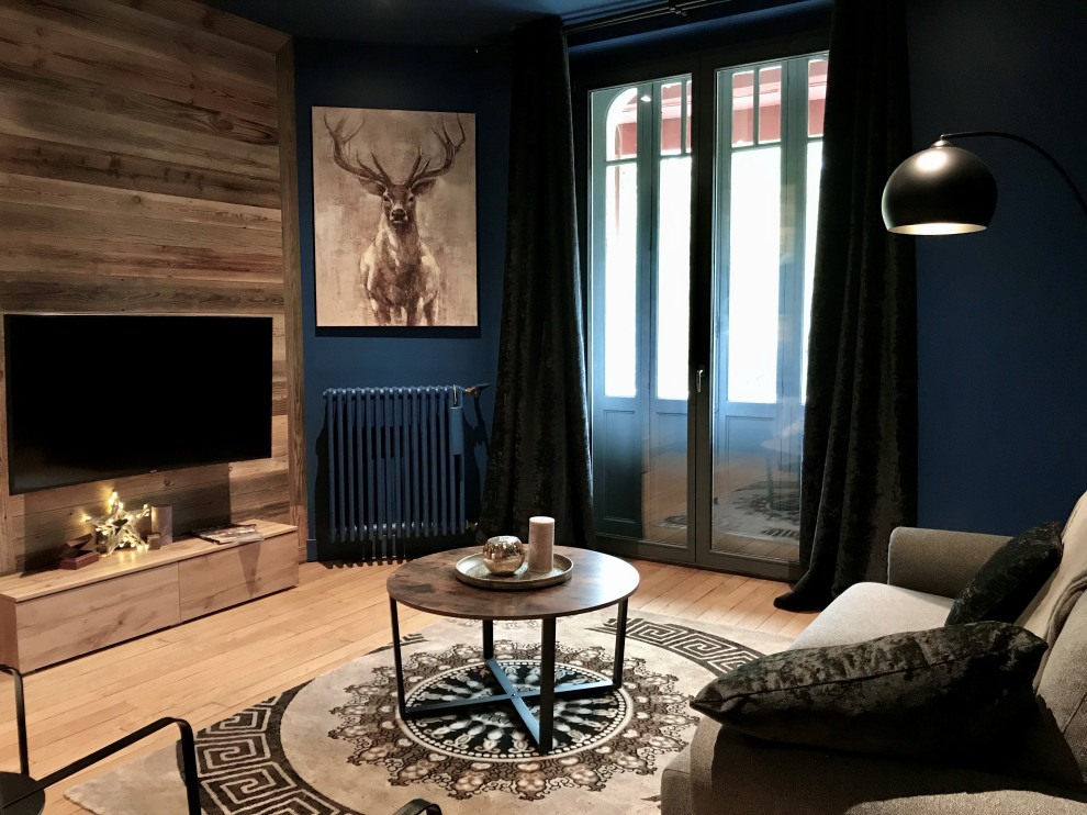 Aménagement de salon in bois With un mur bleu, parquet clair, aucune cheminée, un téléviseur fixé au mur and un sol beige.