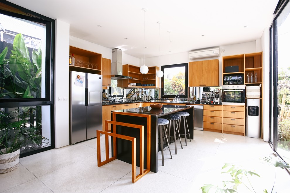 Design ideas for a contemporary l-shaped kitchen in Singapore with flat-panel cabinets, light wood cabinets, stainless steel appliances, with island, white floor and black benchtop.