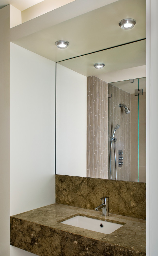 Contemporary bathroom in New York with an undermount sink, limestone benchtops, a corner shower, a one-piece toilet, white walls and limestone floors.