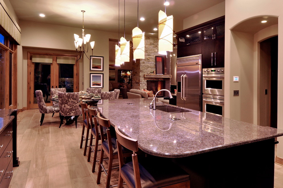 Example of a large transitional l-shaped light wood floor and beige floor eat-in kitchen design in Omaha with a double-bowl sink, flat-panel cabinets, dark wood cabinets, granite countertops, mosaic tile backsplash, stainless steel appliances and an island