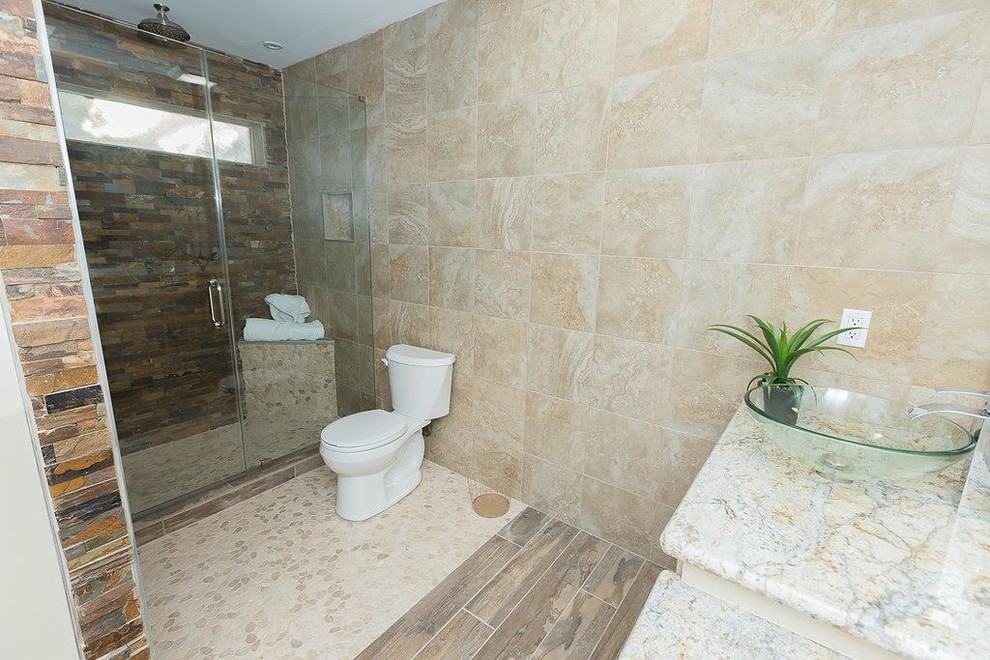 This is an example of a mid-sized contemporary 3/4 bathroom in Houston with raised-panel cabinets, beige cabinets, an alcove shower, a one-piece toilet, beige tile, stone tile, beige walls, ceramic floors, a vessel sink, granite benchtops, beige floor and a hinged shower door.