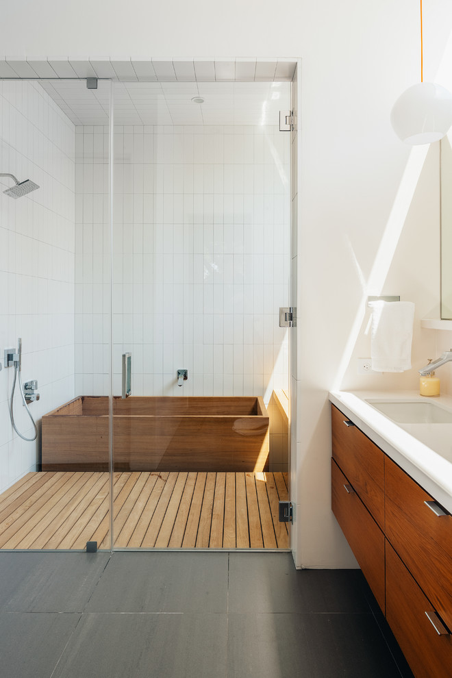 This is an example of a contemporary wet room bathroom in Houston with an undermount sink, flat-panel cabinets, medium wood cabinets, a japanese tub, white tile, white walls and a double vanity.