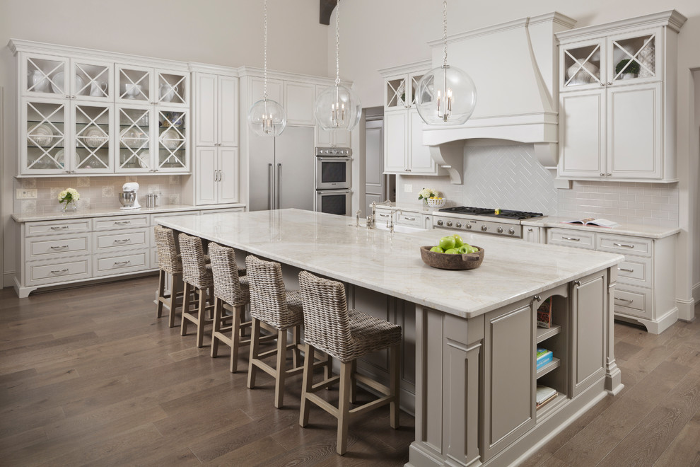 Elegant light wood floor and beige floor kitchen photo in Houston with a farmhouse sink, beige cabinets, beige backsplash, stainless steel appliances, an island, quartzite countertops and recessed-panel cabinets
