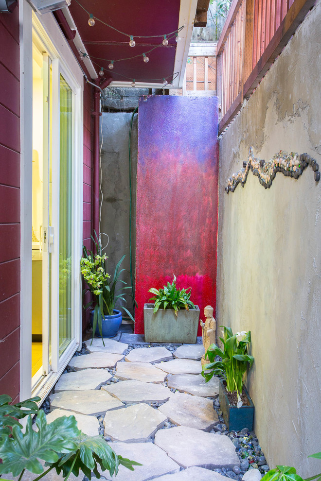 Small eclectic courtyard patio in San Francisco with natural stone pavers and a roof extension.