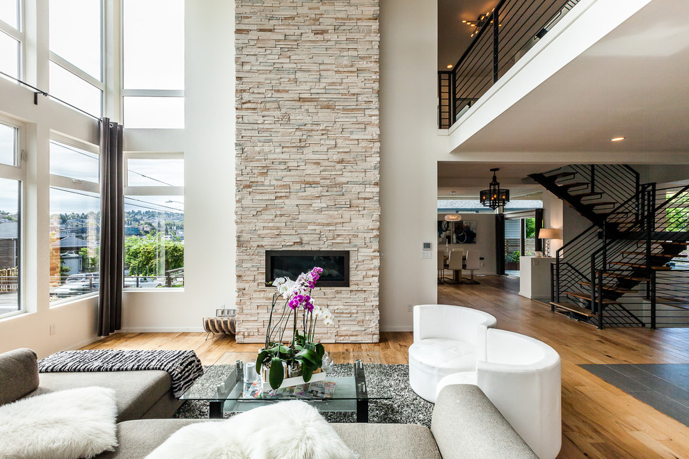 Photo of a large contemporary formal open concept living room in Seattle with white walls, light hardwood floors, a ribbon fireplace, a stone fireplace surround and no tv.