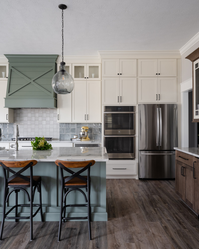 Inspiration for a mid-sized transitional l-shaped eat-in kitchen in Indianapolis with an undermount sink, shaker cabinets, white cabinets, marble benchtops, multi-coloured splashback, stainless steel appliances, medium hardwood floors, with island and white benchtop.