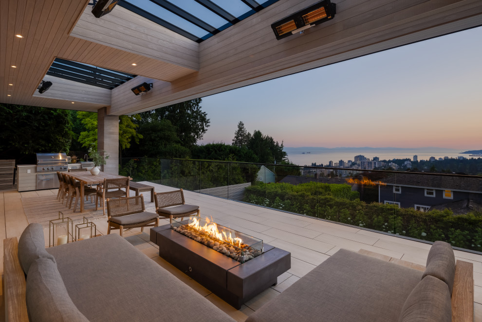 Inspiration for an expansive contemporary back first floor glass railing terrace in Vancouver with an awning.