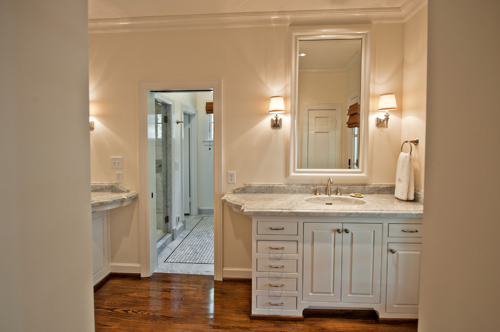 This is an example of an expansive transitional master bathroom in Nashville with an undermount sink, raised-panel cabinets, white cabinets, marble benchtops, an alcove shower, white walls and medium hardwood floors.