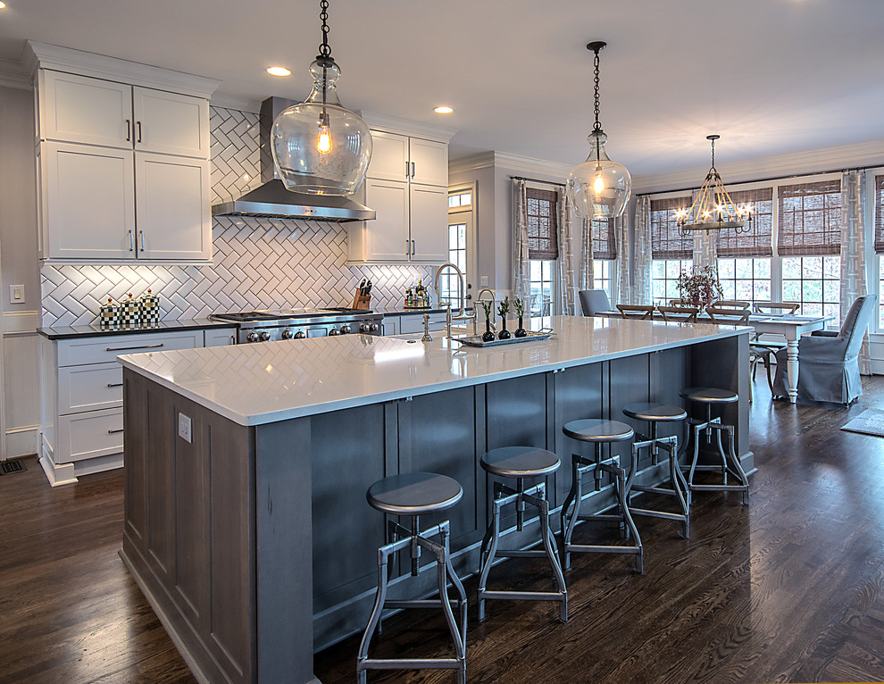 Open concept kitchen - large transitional l-shaped medium tone wood floor and brown floor open concept kitchen idea in Atlanta with a farmhouse sink, shaker cabinets, white cabinets, quartzite countertops, white backsplash, subway tile backsplash, stainless steel appliances and an island