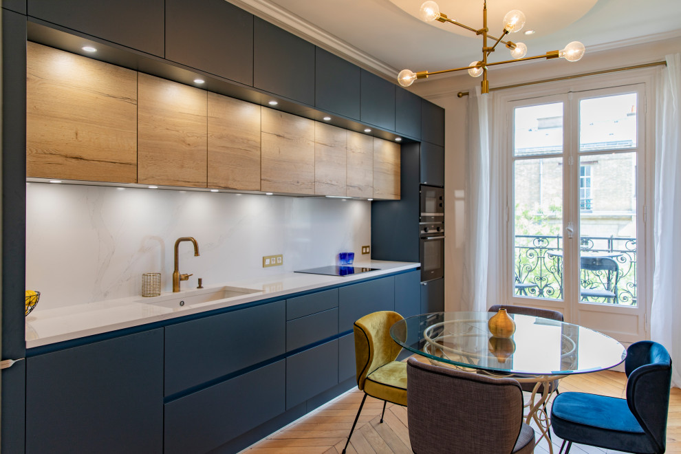 Photo of a large contemporary single-wall eat-in kitchen in Paris with an undermount sink, flat-panel cabinets, blue cabinets, white splashback, porcelain splashback, panelled appliances, porcelain floors, no island, beige floor and white benchtop.
