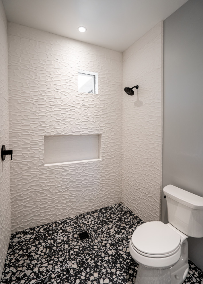 Réalisation d'une salle de bain de taille moyenne avec un placard à porte plane, des portes de placard grises, une douche ouverte, WC séparés, un carrelage gris, des carreaux de porcelaine, un mur gris, un sol en terrazzo, un lavabo encastré, un plan de toilette en quartz, un sol noir, aucune cabine, un plan de toilette blanc, meuble simple vasque et meuble-lavabo suspendu.