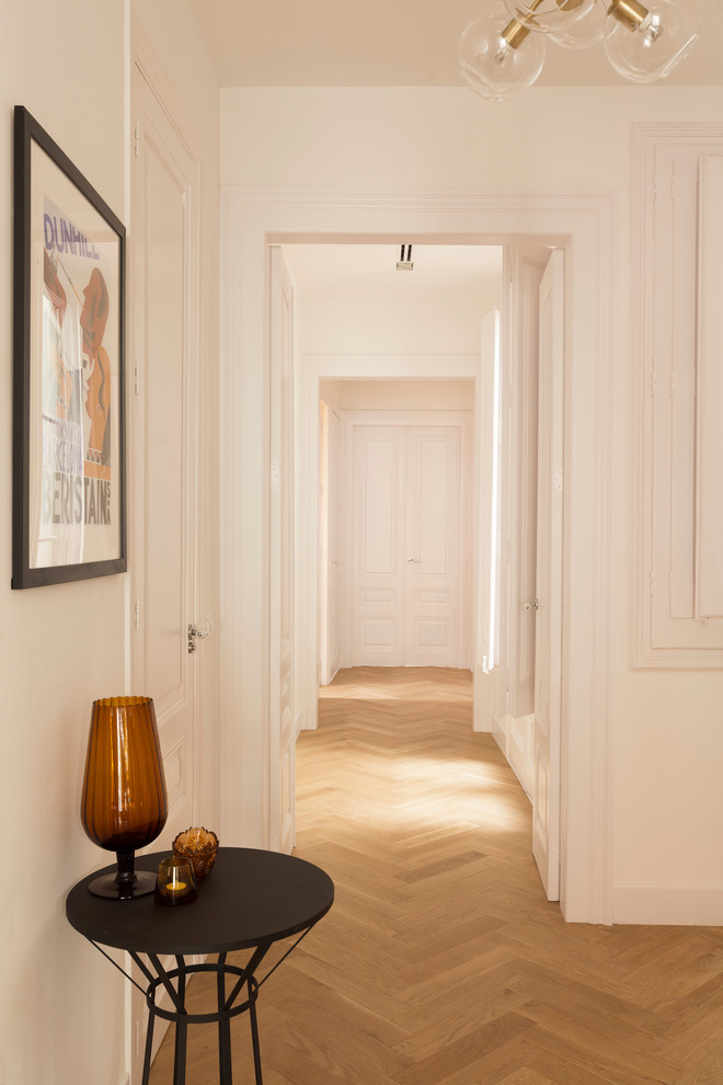 Photo of a mid-sized transitional hallway in Barcelona with white walls and light hardwood floors.