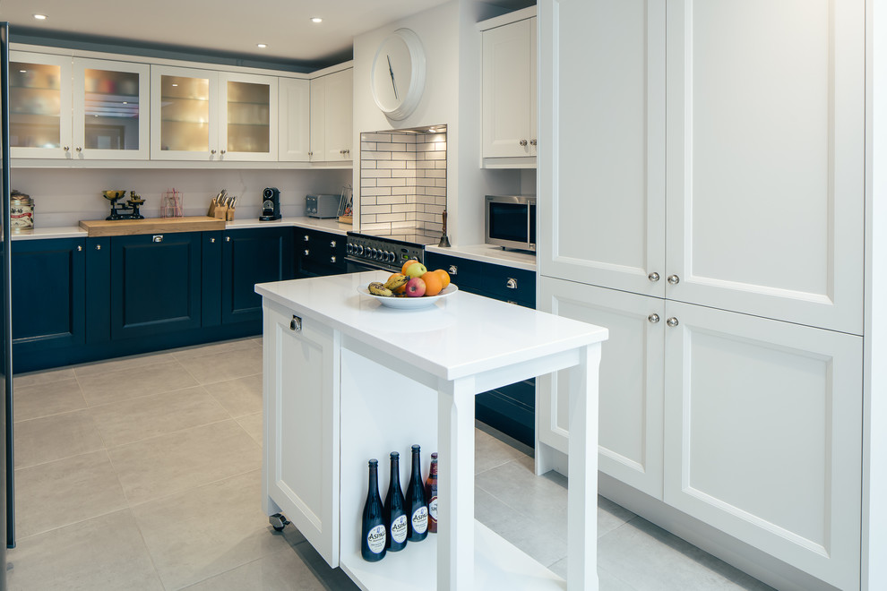 Inspiration for a mid-sized transitional u-shaped eat-in kitchen in Cambridgeshire with a drop-in sink, shaker cabinets, blue cabinets, granite benchtops, white splashback, glass sheet splashback, stainless steel appliances, slate floors, with island and beige floor.