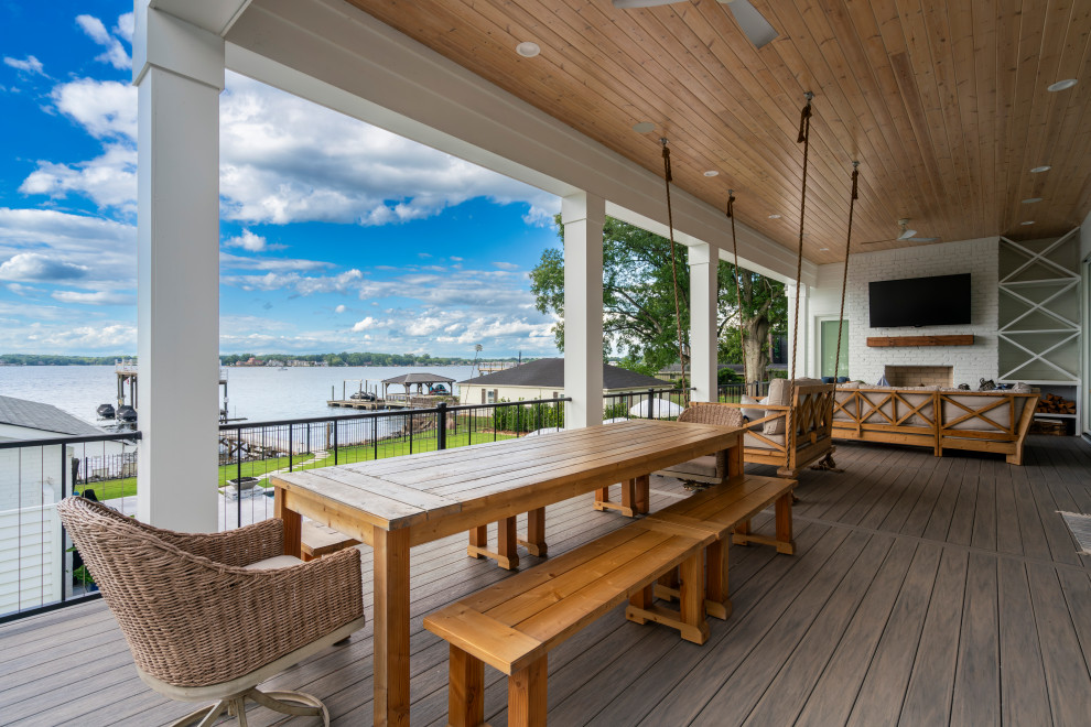 Large beach style back metal railing veranda in Charlotte with a fireplace and decking.