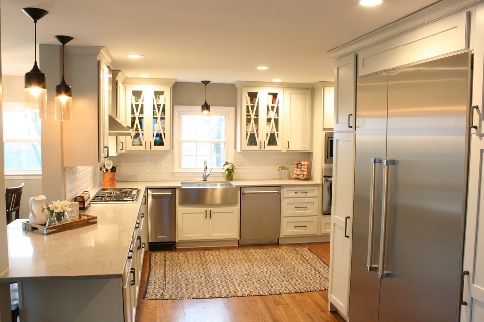 Photo of a transitional eat-in kitchen in Nashville with shaker cabinets, white cabinets, white splashback, stainless steel appliances, no island and a farmhouse sink.