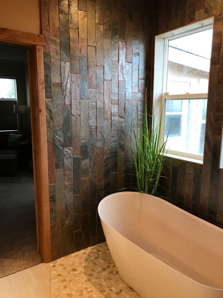 Large mountain style master multicolored tile and slate tile light wood floor and beige floor freestanding bathtub photo with beige walls