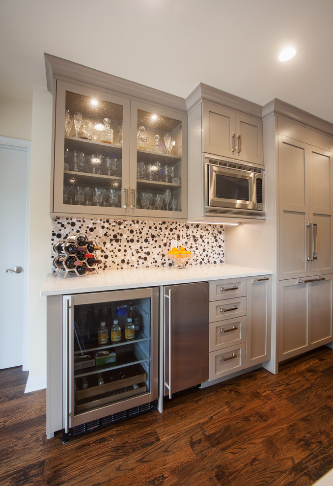 Example of a large trendy medium tone wood floor and brown floor open concept kitchen design with an undermount sink, shaker cabinets, beige cabinets, quartzite countertops, white backsplash, mosaic tile backsplash, stainless steel appliances and an island