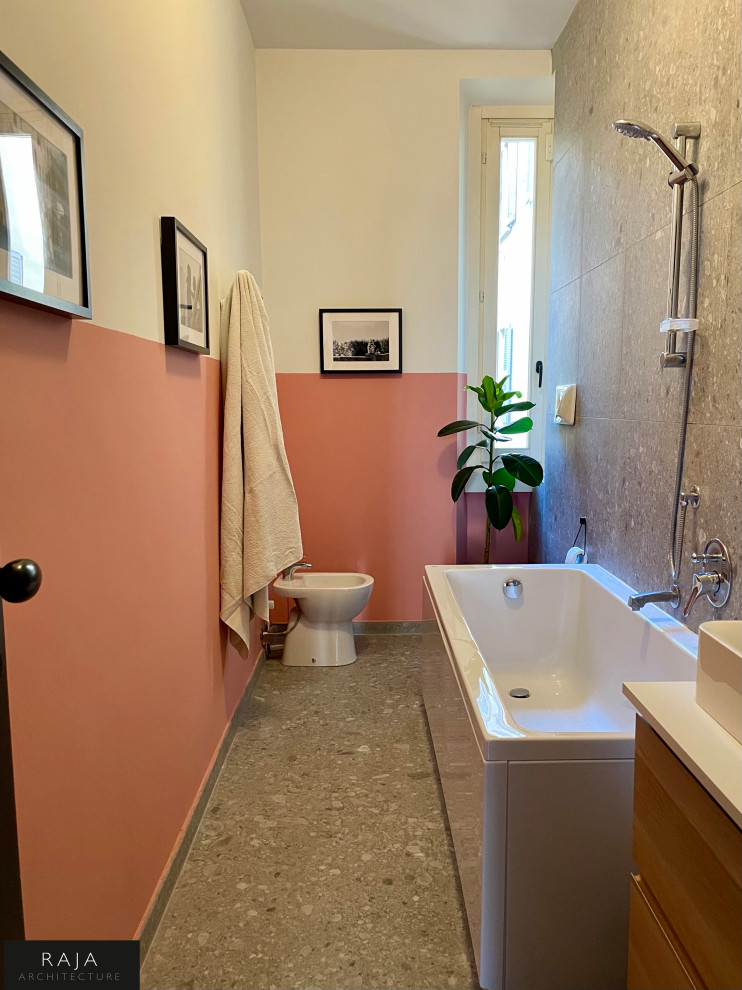 Modern inredning av ett mellanstort vit vitt en-suite badrum, med släta luckor, skåp i ljust trä, ett fristående badkar, en toalettstol med hel cisternkåpa, grå kakel, porslinskakel, rosa väggar, klinkergolv i porslin, ett fristående handfat, laminatbänkskiva och grått golv