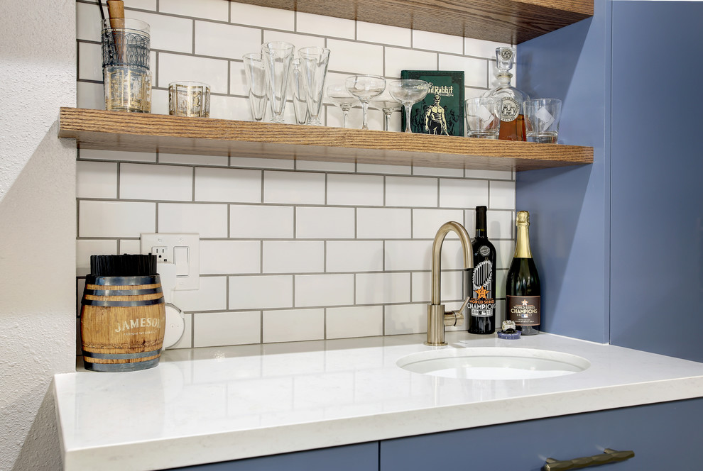 Design ideas for a large eclectic galley wet bar in Houston with an undermount sink, flat-panel cabinets, blue cabinets, quartz benchtops, white splashback, subway tile splashback, laminate floors, grey floor and white benchtop.