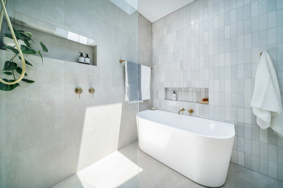 This is an example of a mid-sized contemporary master bathroom in Melbourne with flat-panel cabinets, light wood cabinets, a freestanding tub, a corner shower, gray tile, white tile, white walls, porcelain floors, an undermount sink, engineered quartz benchtops, grey floor, an open shower, white benchtops, a single vanity and a floating vanity.